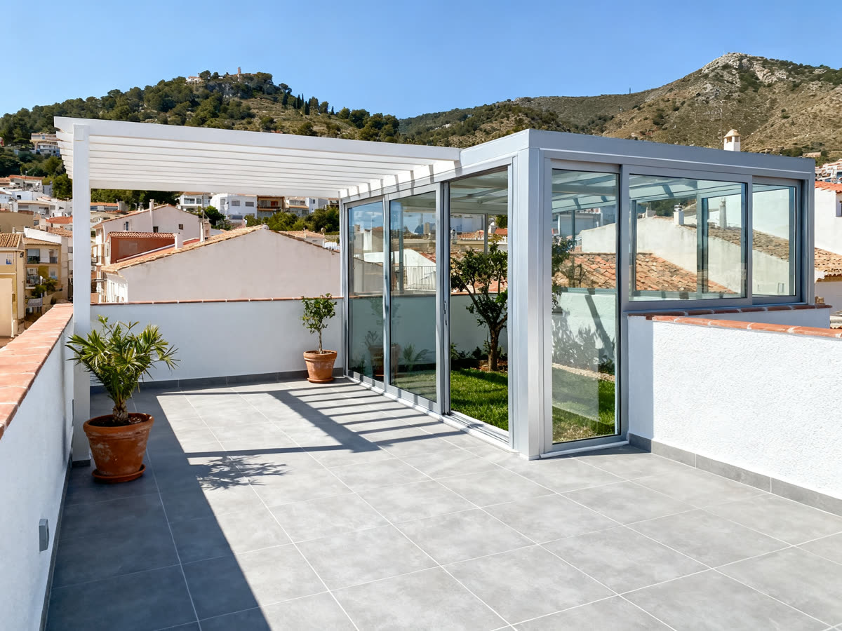 Terraza de una casa adosada con suelo nuevo, pérgola y cerramiento de aluminio y cristal
