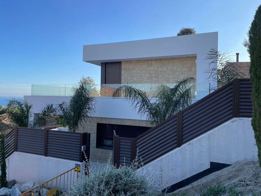 Fachada de vivienda unifamiliar combinando piedra natural y revestimiento blanco